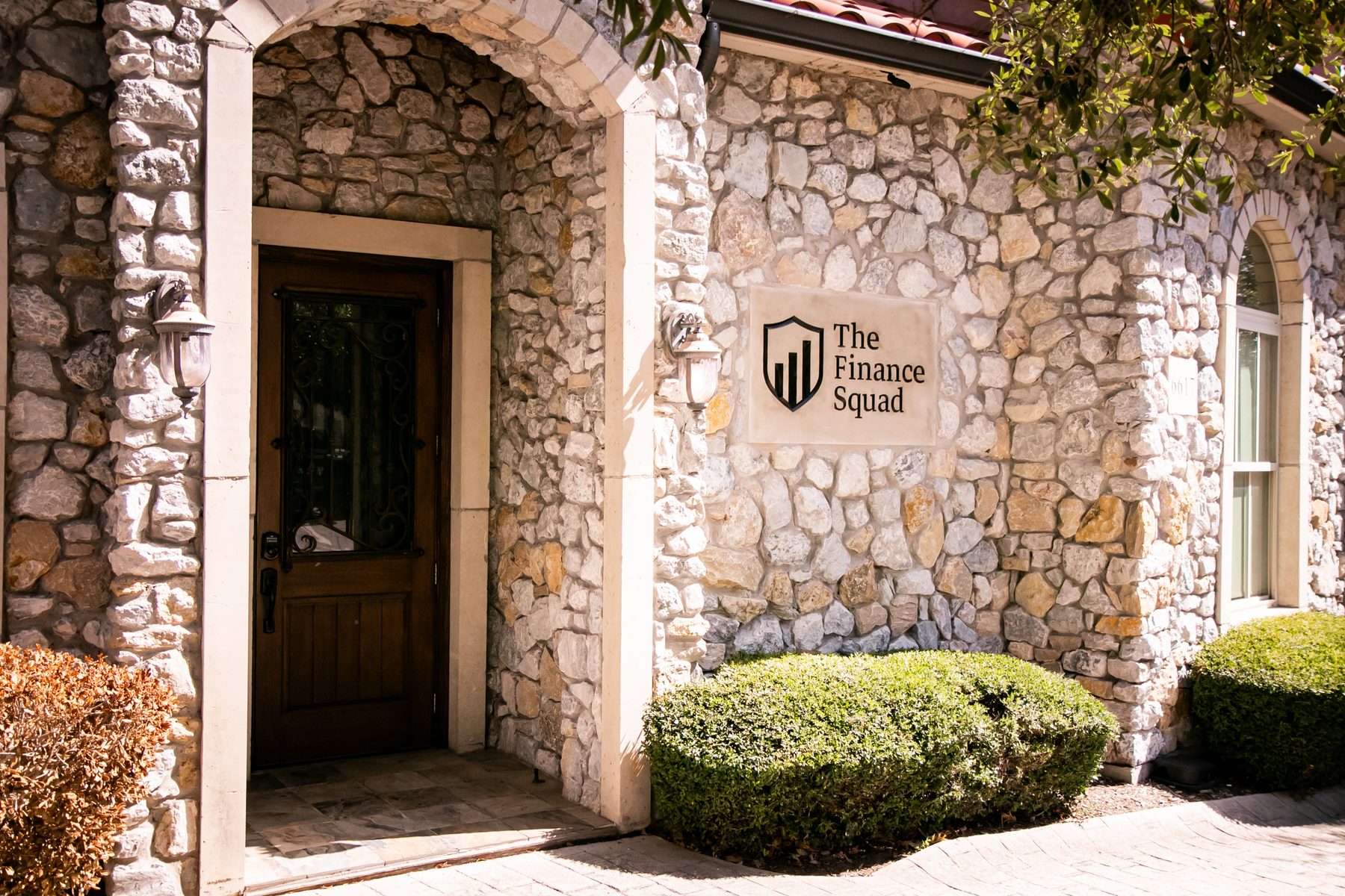 The stone entrance of The Finance Squad office in McKinney, Texas, with the carved sign beside the front door